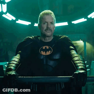 A Man In A Batman Costume Is Standing In A Dark Room . GIF