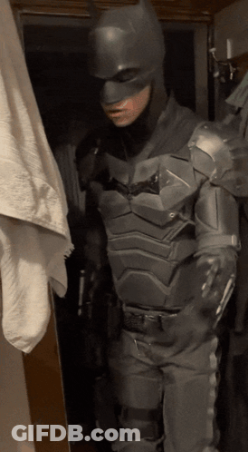 A Man In A Batman Costume Is Standing Next To A Towel GIF