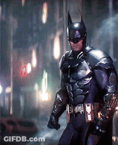 A Man In A Batman Costume Is Walking Down A Street At Night GIF
