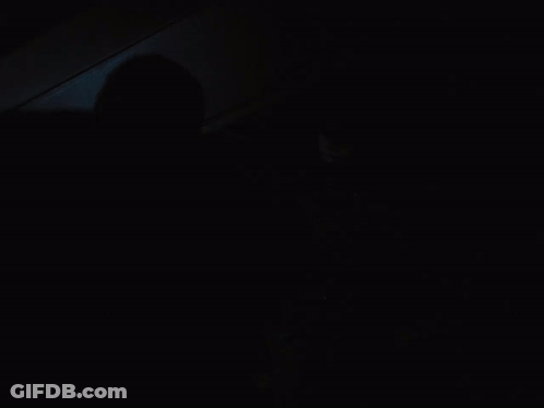 A Man In A Batman Costume Stands In The Dark GIF