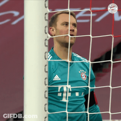 A Man In A Bayern Munich Jersey Stands In Front Of A Soccer Net GIF