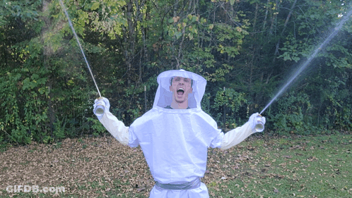 A Man In A Beekeeper Costume Is Holding Two Swords GIF