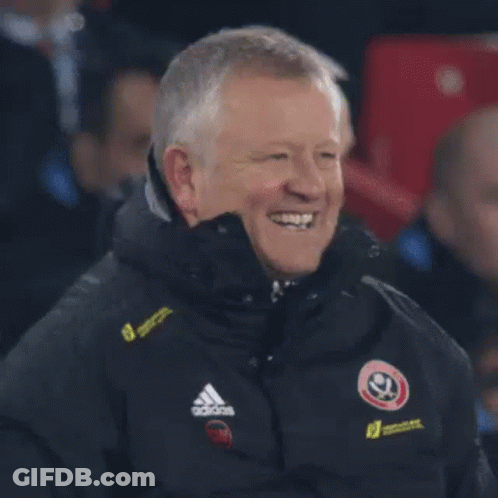 A Man In A Black Adidas Jacket Is Standing In Front Of A Crowd . GIF