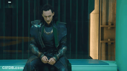 A Man In A Black And Green Costume Is Sitting On A Bench GIF