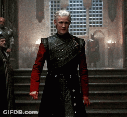 A Man In A Black And Red Armor Stands On Stairs GIF