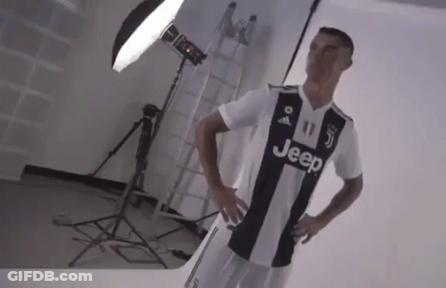 A Man In A Black And White Jeep Jersey Is Standing In Front Of A Light . GIF