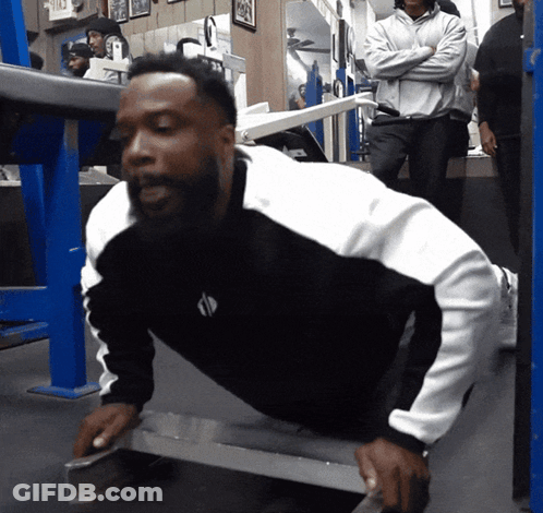 A Man In A Black And White Shirt Is Doing Push Ups On A Bench GIF