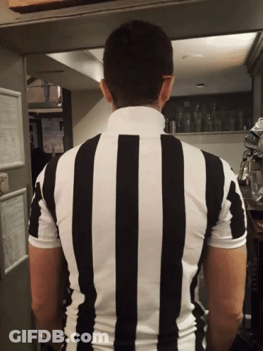 A Man In A Black And White Striped Shirt Stands In A Kitchen GIF