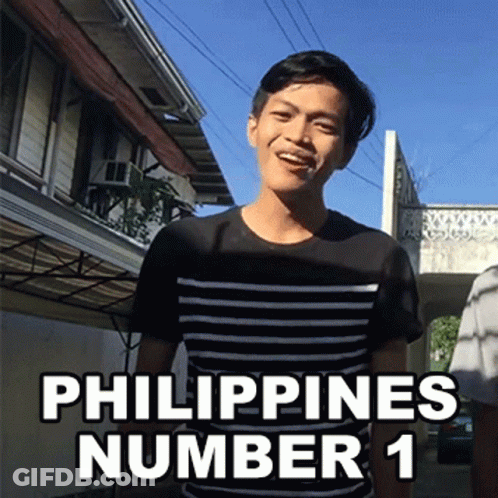 A Man In A Black And White Striped Shirt Stands In Front Of A Building With The Words Philippines Number 1 Above Him GIF