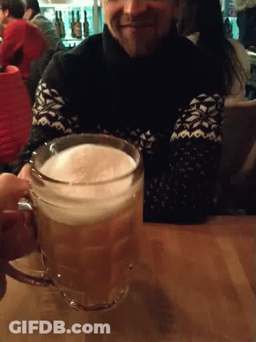 A Man In A Black And White Sweater Holds A Glass Of Beer GIF
