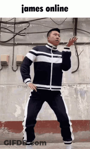 A Man In A Black And White Tracksuit Is Dancing In Front Of A Wall With The Words James Online Above Him GIF