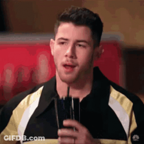 A Man In A Black And Yellow Jacket Is Holding A Glass Of Water . GIF