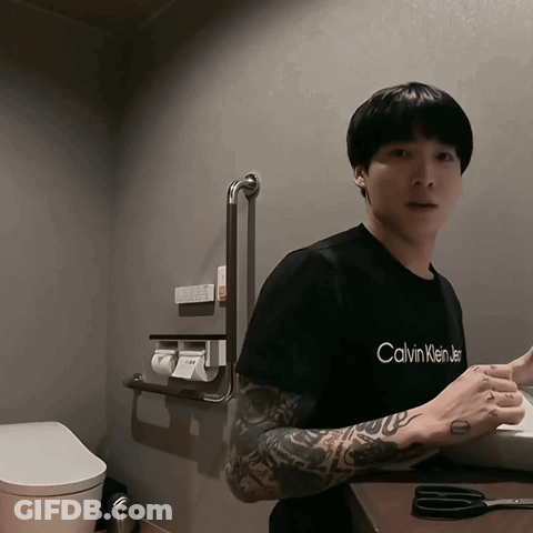 A Man In A Black Calvin Klein T-Shirt Is Standing In A Bathroom GIF