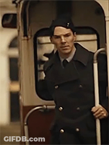 A Man In A Black Coat And Hat Is Standing In A Bus GIF
