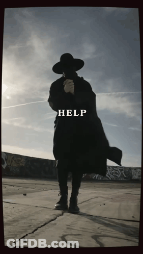 Man In Black Coat And Hat In Front Of Help Wall GIF
