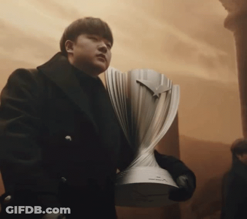 A Man In A Black Coat Holds A Silver Trophy GIF