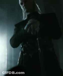 A Man In A Black Coat Holds A Sword In His Hands GIF
