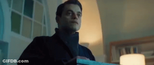 A Man In A Black Coat Is Holding A Box In A Dark Room . GIF