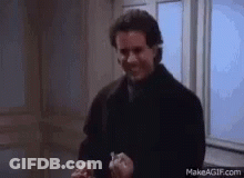 A Man In A Black Coat Is Smiling While Holding A Bottle Of Pills . GIF