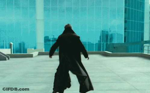 A Man In A Black Coat Is Standing On A Rooftop GIF