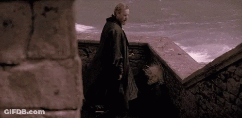 A Man In A Black Coat Is Walking Down Stairs . GIF