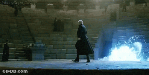 A Man In A Black Coat Is Walking In Front Of Stairs With A Blue Light Coming Out Of Them GIF