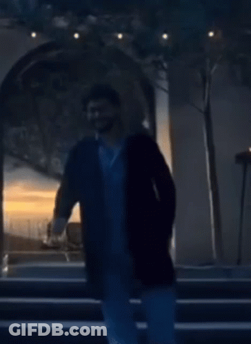 A Man In A Black Coat Stands In Front Of A Building GIF