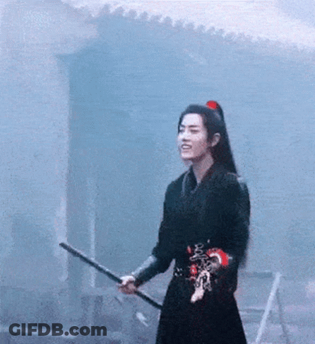 A Man In A Black Dress Is Holding A Sword In His Hand . GIF