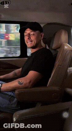 A Man In A Black Hat Is Sitting In The Back Seat Of A Car . GIF