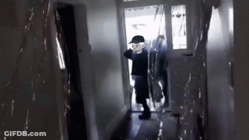 A Man In A Black Hat Is Walking Through A Hallway GIF