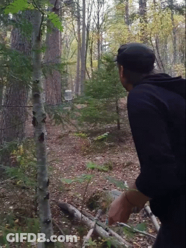 A Man In A Black Hat Stands In The Woods GIF