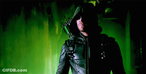 A Man In A Black Hooded Jacket Is Holding A Green Arrow GIF