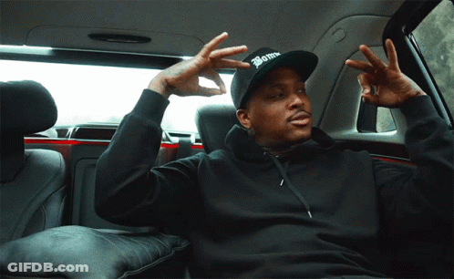 A Man In A Black Hoodie And A Black Hat With The Word Bomb On It Is Sitting In The Back Seat Of A Car GIF