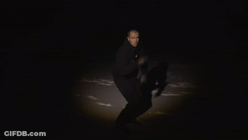 A Man In A Black Hoodie Holds A Piece Of Red Paper With The Number 2123 On It GIF