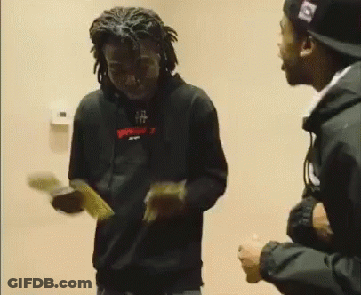 A Man In A Black Hoodie Is Holding A Bunch Of Money While Standing Next To Another Man In A Hat . GIF