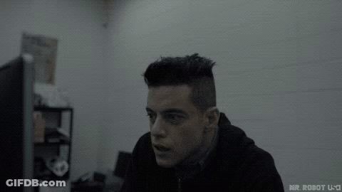 A Man In A Black Hoodie Is Sitting In Front Of A Computer Screen . GIF