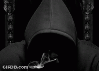 A Man In A Black Hoodie Is Smoking A Cigarette In A Black And White Photo . GIF