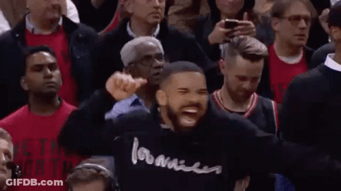 A Man In A Black Hoodie Is Standing In Front Of A Crowd Of People . GIF