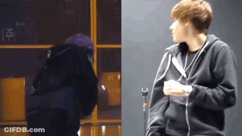 A Man In A Black Hoodie Stands Next To A Microphone GIF