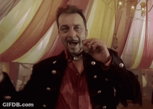 A Man In A Black Jacket And Red Shirt Is Holding Something In His Mouth While Standing In Front Of A Tent GIF