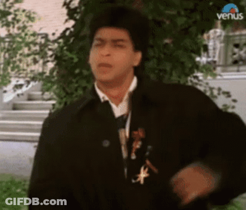 A Man In A Black Jacket And Tie Is Standing In Front Of A Tree And Stairs . GIF