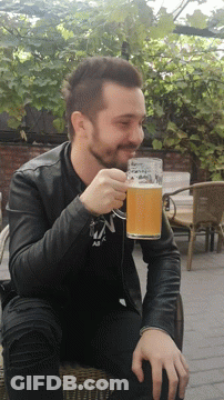 A Man In A Black Jacket Drinks From A Glass With The Letter N On It GIF