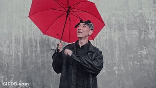 A Man In A Black Jacket Holds A Red Umbrella That Says ' Umbrella ' On It GIF