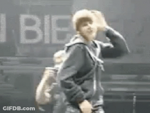 A Man In A Black Jacket Is Dancing On A Stage In Front Of A Sign That Says I Bie . GIF