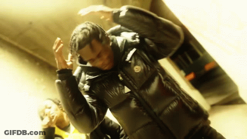 A Man In A Black Jacket Is Dancing With Another Man In A Yellow Jacket . GIF
