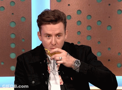 A Man In A Black Jacket Is Drinking A Drink GIF