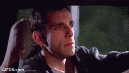A Man In A Black Jacket Is Driving A Car And Looking Out The Window GIF