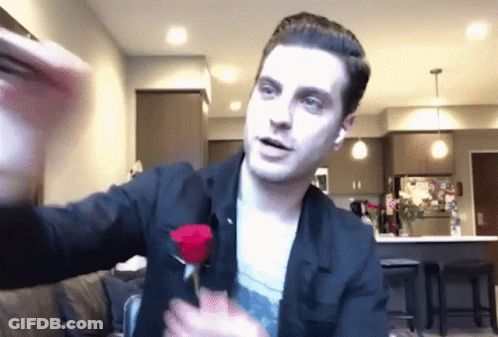 A Man In A Black Jacket Is Holding A Red Rose In His Hands GIF