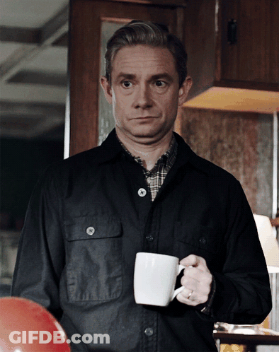 A Man In A Black Jacket Is Holding A White Coffee Cup GIF