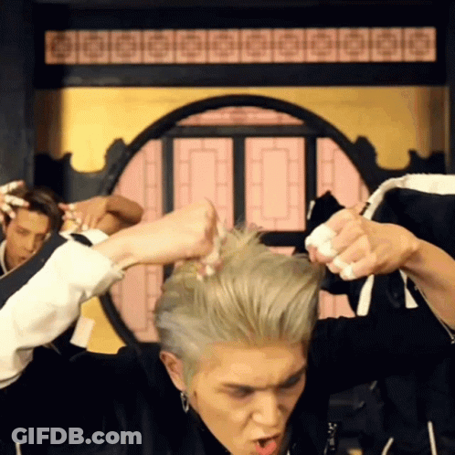 A Man In A Black Jacket Is Holding His Hair In A Circle GIF